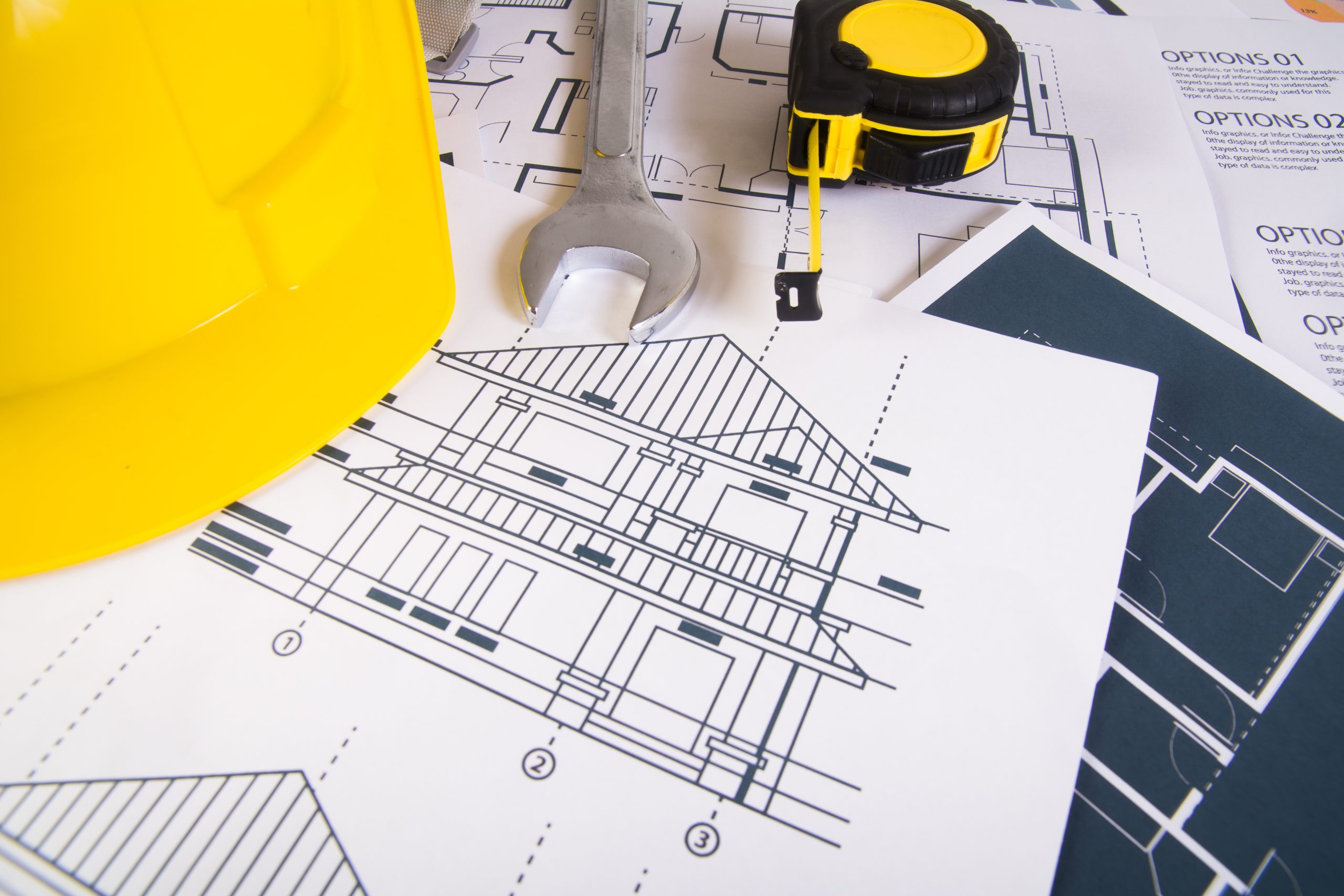 Engineer workplace with blueprints, protractor and safety helmet.